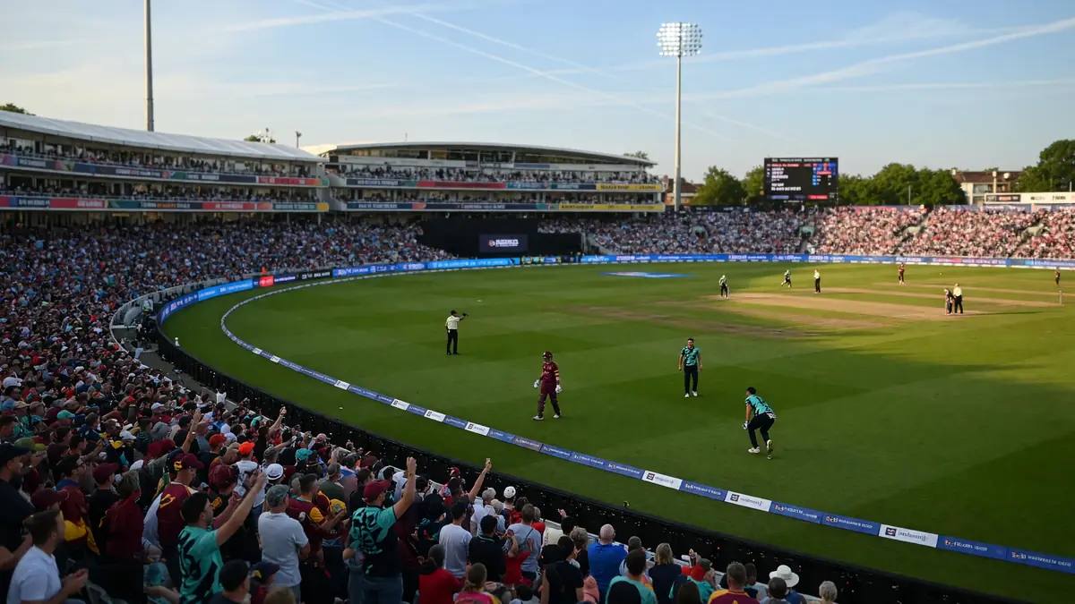 Wide evening view of a packed English cricket ground under floodlights with the outfield prepared for a short-format fixture, framing the Edgbaston build-up to Birmingham Phoenix against Welsh Fire
