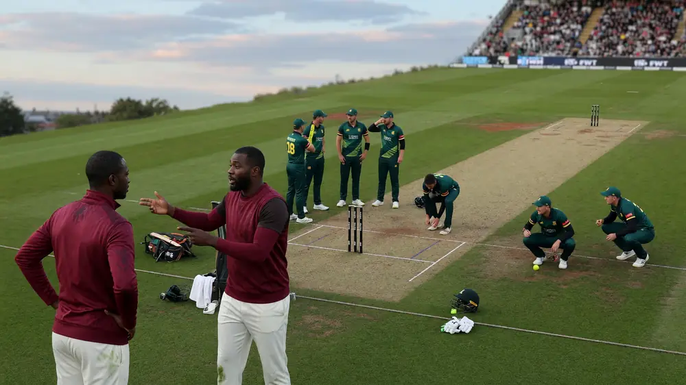 Medium tactical view of fielders set in a short-format ring on a floodlit square, with the bowler at the top of the mark and batters waiting at the crease